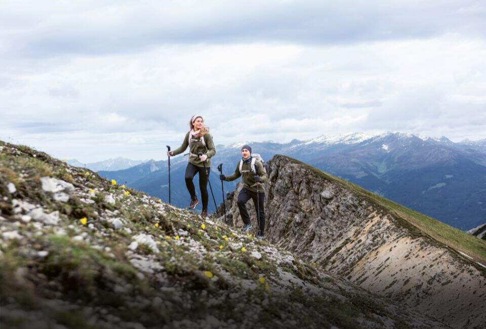 Eine Frau und ein Mann sitzen vor einer Holzhütte in den Bergen.