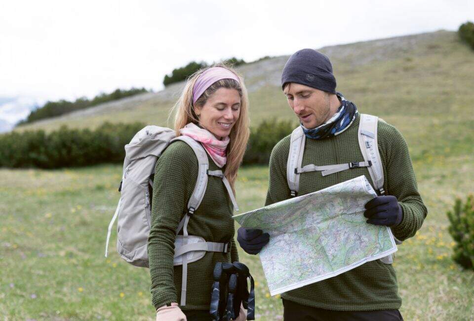 Ein Mann und eine Frau tragen Outdoorkleidung stehen auf einem Berg.