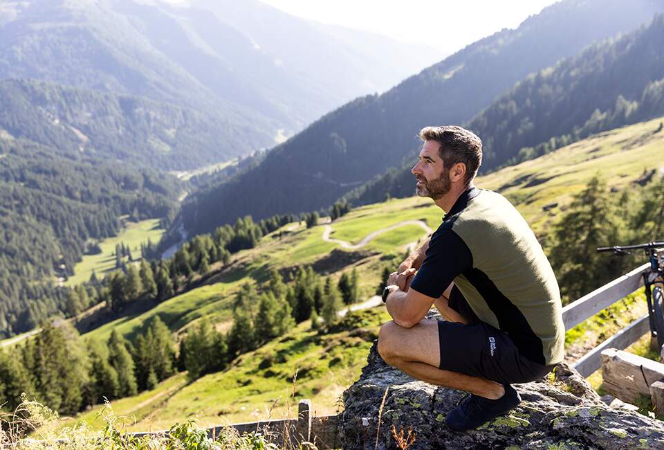 Ein Mann trägt Outdoorkleidung und sitzt auf einem Berg.